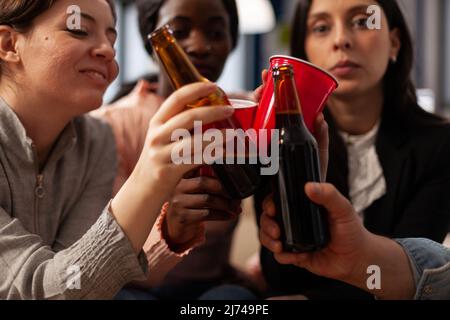 Les gens d'affaires se sont mis à prendre des verres et des bouteilles de bière lors de la fête de bureau après le travail. Rendez-vous entre amis pour prendre un verre après le travail, en faisant des gestes de salut pour la fête. Gros plan. Banque D'Images