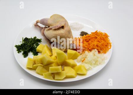 De la viande de caille biologique fraîche et crue avec des ingrédients pour cuisiner de la soupe saine. Caille brute, pommes de terre coupées fraîches, carottes, oignons, persil congelé et épices sur le t Banque D'Images