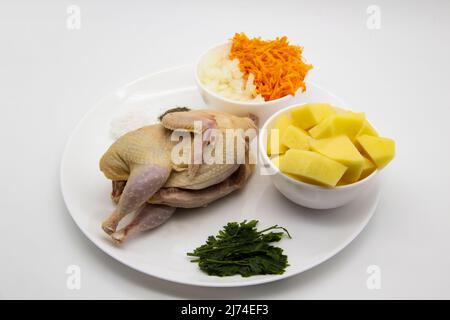 De la viande de caille biologique fraîche et crue avec des ingrédients pour cuisiner de la soupe saine. Caille brute, pommes de terre coupées fraîches, carottes, oignons, persil congelé et épices sur le t Banque D'Images
