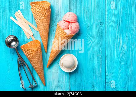 Glace aux baies, gaufres et cuillère sur fond bleu. Banque D'Images