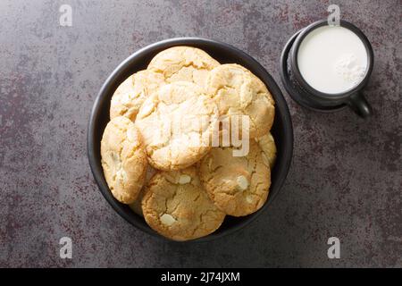 Petits gâteaux moelleux aux noix de macadamia et au chocolat blanc servis avec du lait en gros plan sur la table. Vue horizontale du dessus Banque D'Images