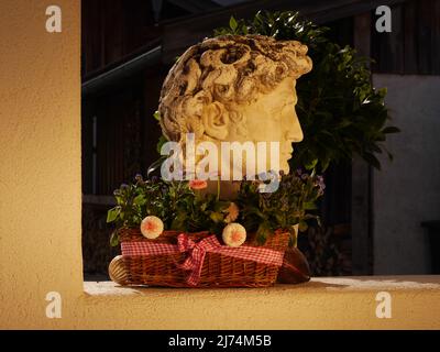 plantes dans un panier de saule devant une sculpture Banque D'Images