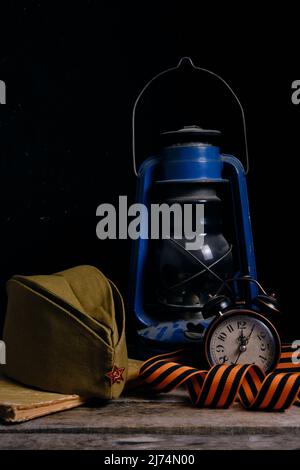 Soldats russes Cap, St. George ruban, vieux livre et un réveil avec lampe au kérosène. Le jour de la victoire est le 9th mai Banque D'Images