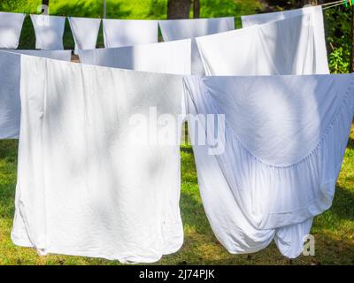 linge blanc frais suspendu sur une corde à linge en plein air dans un camp d'été dans une forêt, gros plan Banque D'Images