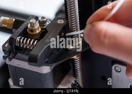 Man Hand sets filament pour imprimante 3D, moteur pas à pas d'imprimante 3D et macro-shot d'entrée de filament, concept d'impression, machine industrielle, technologie de Banque D'Images