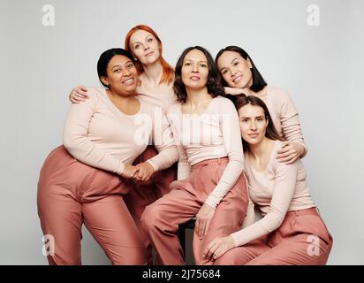 Portrait de vraies femmes souriantes de différentes races et âges debout et assis ensemble sur fond blanc Banque D'Images