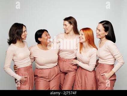 Riant des femmes multiethniques dans les mêmes tenues en regardant les uns les autres tout en discutant ensemble Banque D'Images