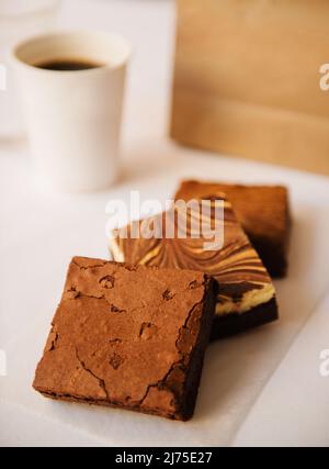 assortiment de brownies au chocolat et au fromage à la crème avec café et sac en papier à l'arrière-plan Banque D'Images