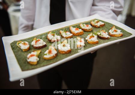 Un serveur sert des hors-d'œuvre de pain grillé avec du fromage et des herbes lors d'un événement Banque D'Images