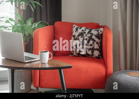 Bureau à la maison avec un ordinateur portable et une tasse de café sur une table basse. Banque D'Images