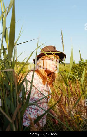 Gros plan sur le flou artistique portrait extérieur de la jeune femme blonde près du roseau et de l'herbe de pampas. Ombres d'art végétal. Femme souriante sur la prairie. Santé mentale Banque D'Images