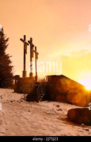 Lumière dorée depuis le coucher du soleil, en heurtant les trois croix sur le Kreuzberg pendant une tempête de neige légère. Le Kreuzberg fait partie des montagnes Rhon en Allemagne an Banque D'Images