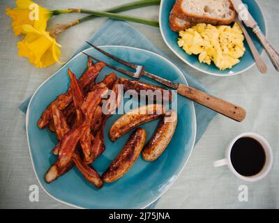 Plateau de saucisses et de bacon; café et œufs en arrière-plan Banque D'Images