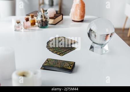 KIEV, UKRAINE - 23 FÉVRIER 2022: Cartes de tarot et orbe magique près de bougies floues sur la table Banque D'Images