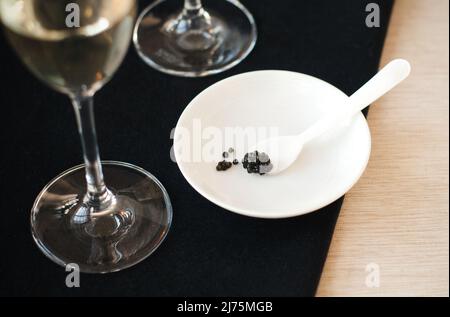 Cuillère avec caviar noir sur une assiette ; verre de champagne Banque D'Images