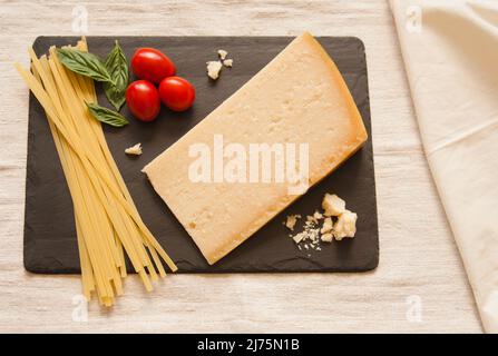 Un coin de parmesan avec des pâtes séchées, des tomates et du basilic sur la salade Banque D'Images