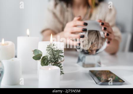 Vue rognée des bougies allumées près du tarot et du milieu flou avec orbe à la maison Banque D'Images