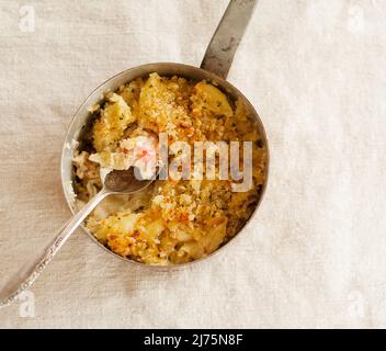 Pot de homard Mac et de fromage avec une cuillère; cuillère retirée Banque D'Images