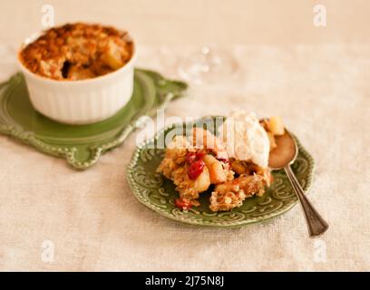 Une portion de pomme Cranberry Cobbler avec de la crème glacée sur une petite assiette verte Banque D'Images