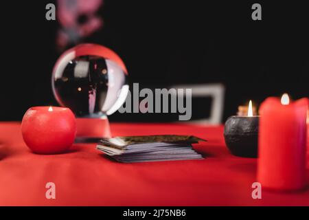 Cartes de Tarot près de bougies allumées et orbe flou sur noir Banque D'Images