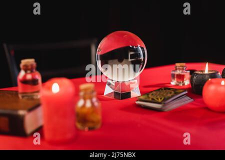 Orbe magique près des cartes de tarot et des bougies sur la table isolée sur noir Banque D'Images