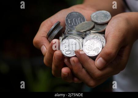 Un enfant asiatique tient la monnaie indonésienne, Rupiah, dans un foyer peu profond Banque D'Images