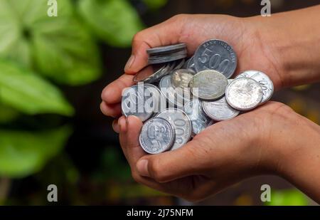 Un enfant asiatique tient la monnaie indonésienne, Rupiah, dans un foyer peu profond Banque D'Images