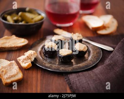 Pruneaux farcis avec foie gras sur un plat métallique; pain et foie gras; cornichons; vin Banque D'Images