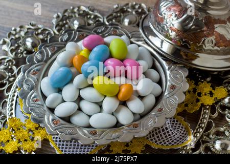 Tons traditionnels, blancs et pastel, bonbons aux amandes enrobés de chocolat dans un bol rétro argenté, sur une surface en bois Banque D'Images