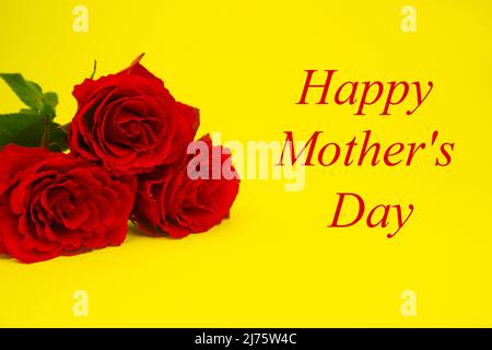 Roses rouges pour maman sur fond jaune, texte BONNE FÊTE DES MÈRES. Banque D'Images