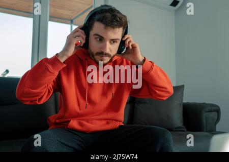 Musique, jeune homme porte des écouteurs pour écouter de la musique dans sa chambre, casque serre-tête Banque D'Images