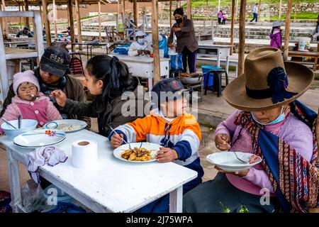 Une famille péruvienne manger un repas au marché du dimanche dans le village de Chinchero, la Vallée Sacrée, province d'Urubamba, Pérou. Banque D'Images