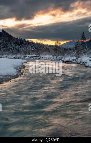 Nuages denses au coucher du soleil dans les prés d'Isar près de Wallgau dans le Karwendel, avec le lit de crique / cours d'eau en premier plan Banque D'Images