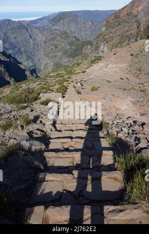 Ombre d'une randonneur femelle prenant des photos sur le sentier de randonnée rural de Pico Ruivo à Pico Arieiro à Madère, Portugal, Europe. Photo de Matheisl Banque D'Images