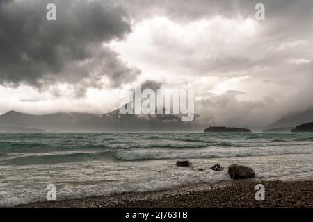 Une puissante tempête avec les vagues, le vent et les nuages sur la rive de Walchensee dans les Alpes bavaroises. En arrière-plan, la petite île de Sassau et l'Herzogstand entre les nuages. Banque D'Images