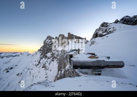 Le télescope, musée à la fosse Karwendel à la station supérieure du Karwendelbahn à Mittenwald dans le Karwendel, en hiver avec neige, glace et lever du soleil. Le Karwendelköpfe au-dessus et le Werdenfelser Land dans la vallée, la structure avec la station de montagne se situe entre la roche et la neige. Banque D'Images