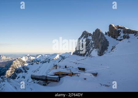 Le télescope, musée à la fosse Karwendel à la station supérieure du Karwendelbahn à Mittenwald dans le Karwendel, en hiver avec neige, glace et lever du soleil. Le Karwendelköpfe au-dessus et le Werdenfelser Land dans la vallée, la structure avec la station de montagne se situe entre la roche et la neige. Banque D'Images