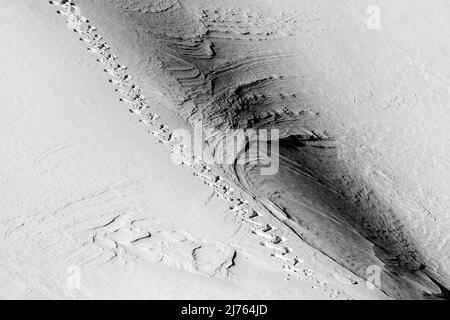 Une seule piste de raquettes dans le Karwendel sur une pente de montagne dans la neige. Le terrain escarpé montre des structures dans la neige. Banque D'Images