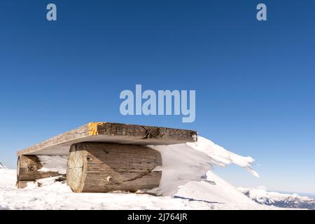 Un banc à la station supérieure du Karwendelbahn sur le Karwendel occidental, dans la neige et la glace, avec des glaçons bizarres allant horizontalement loin du siège. Banque D'Images