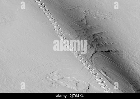 Une seule piste de raquettes dans le Karwendel sur une pente de montagne dans la neige. Le terrain escarpé montre des structures dans la neige. Banque D'Images