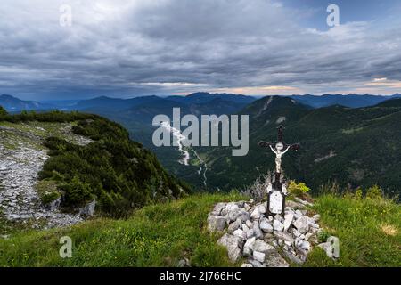 La petite croix de sommet du Vorderskopf dans des nuages denses et l'atmosphère de soirée, en arrière-plan le Rissbach dans le Karwendel, séché grâce à la puissance de l'eau, et vue vers Vorderriss. Banque D'Images