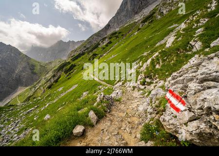 Marquage de route sur le sentier de randonnée jusqu'à la Lamsenjochhütte en dessous de la Lamsenspitze dans le Karwendel, le chemin serpente le long de la montagne, en arrière-plan dans la petite hutte Banque D'Images