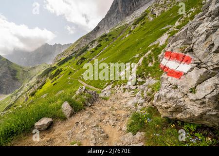 Marquage de route sur le sentier de randonnée jusqu'à la Lamsenjochhütte en dessous de la Lamsenspitze dans le Karwendel, le chemin serpente le long de la montagne, en arrière-plan dans la petite hutte Banque D'Images