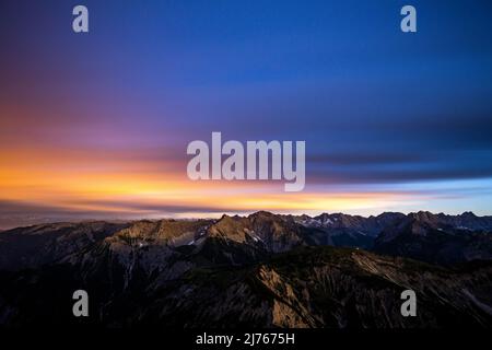 Rouge nocturne peu après le coucher du soleil depuis le sommet du Mondscheinspitze, au milieu du Karwendel, une partie des Alpes. La longue exposition atténue les nuages et reflète la lumière de la nuit. Banque D'Images