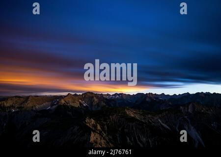 Rouge nocturne peu après le coucher du soleil depuis le sommet du Mondscheinspitze, au milieu du Karwendel, une partie des Alpes. La longue exposition atténue les nuages et reflète la lumière de la nuit. Banque D'Images