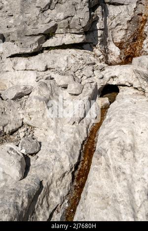 Un petit ressort étroit dans la roche stérile du Karwendel, un pont de roche le traverse. Pris en dessous de l'Östliche Karwendelspitze dans les Alpes tyroliennes. Banque D'Images