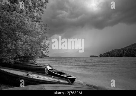 Tempête à l'amarrage du bateau à Niedernach sur le lac Walchen. Plusieurs bateaux de pêche se trouvent sur la plage, en arrière-plan la petite île de Sassau et entre les nuages le Herzogstand. Banque D'Images