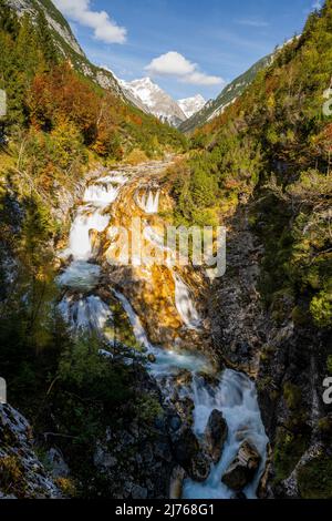 Le ruisseau Karwendelbach près de Scharnitz sur le Karwendelsteg en automne. La lumière du soleil fait briller les rochers, tandis que, en arrière-plan, les sommets enneigés se tiennent contre un ciel bleu. Banque D'Images