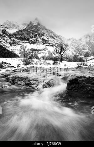 Le Rissbach à la grande Ahornboden dans l'Engtal/ les Hinterriss dans le Tyrol. En arrière-plan, les murs dominants de Laliderer et un vieux érable, tandis qu'en premier plan, le courant montre un jet puissant lorsque le ruisseau coule entre deux roches. Pris pendant la neige fraîche en septembre. Banque D'Images