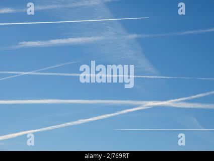 Plusieurs avions contrent le ciel bleu dans un état de survol, avec deux avions faisant activement de nouveaux sentiers en haut et en bas, à la direction opposée Banque D'Images